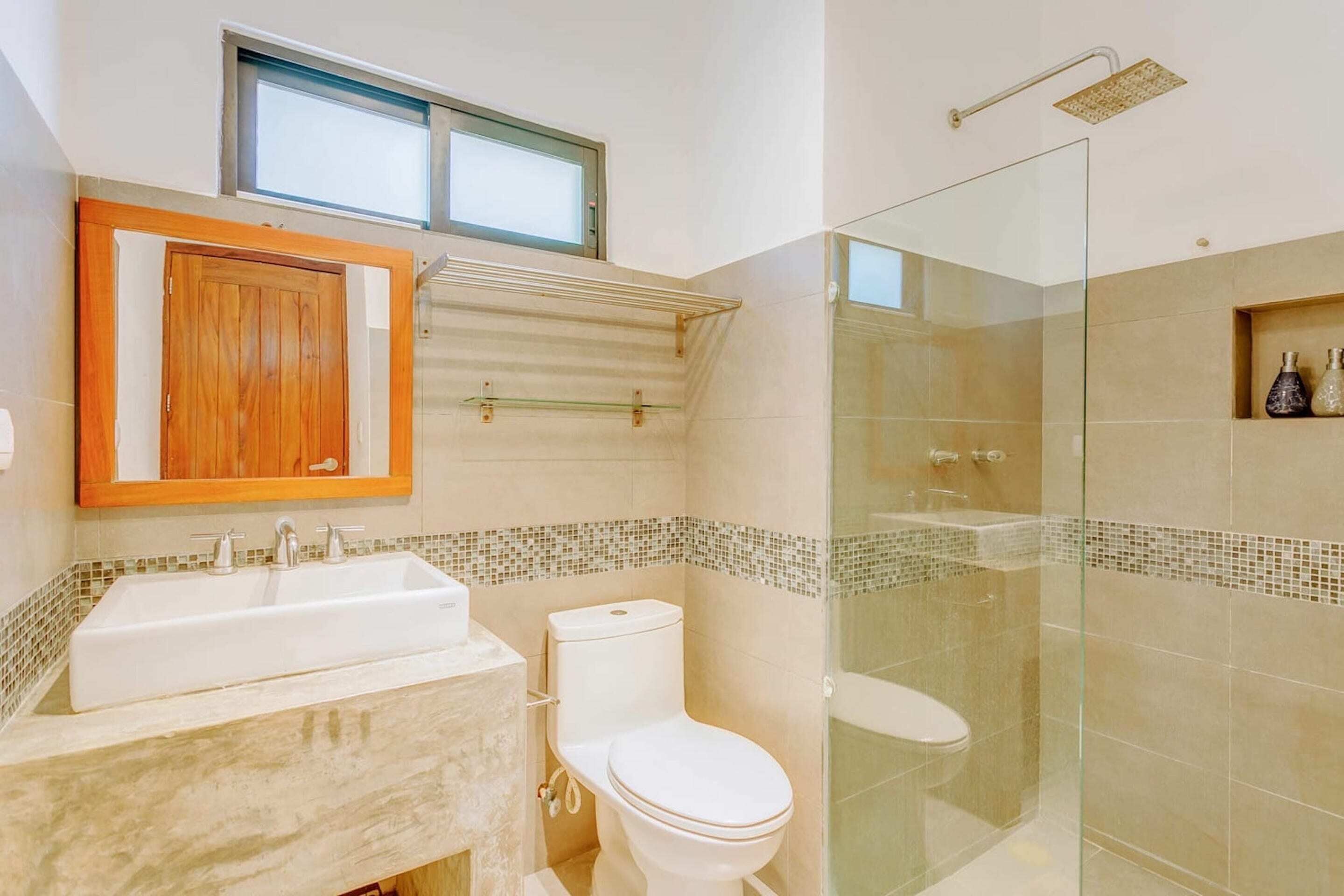 A bathroom with a large sink, toilet, and glass-enclosed shower area.