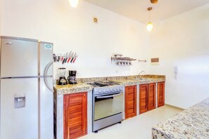 Une cuisine équipée d’un réfrigérateur, d’une cuisinière, d’un four et de meubles de rangement en bois.