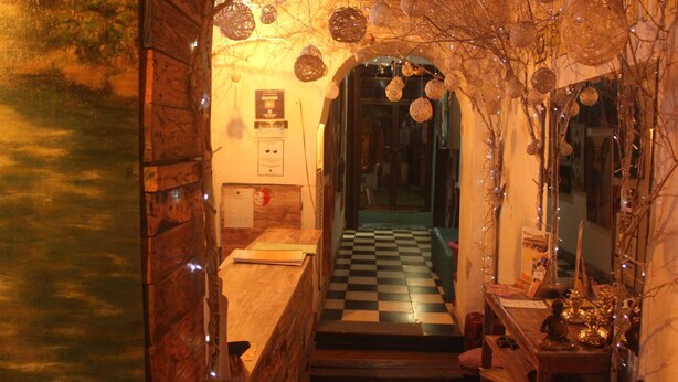 A narrow hallway with a checkered floor, wooden walls, and a small table with decorative items. - Hostal La Antigua Capsula (Cali)
