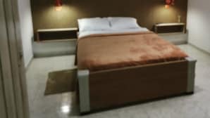A bedroom with a bed, two bedside tables, and wall-mounted lights. - Hostal La Antigua Capsula (Cali)