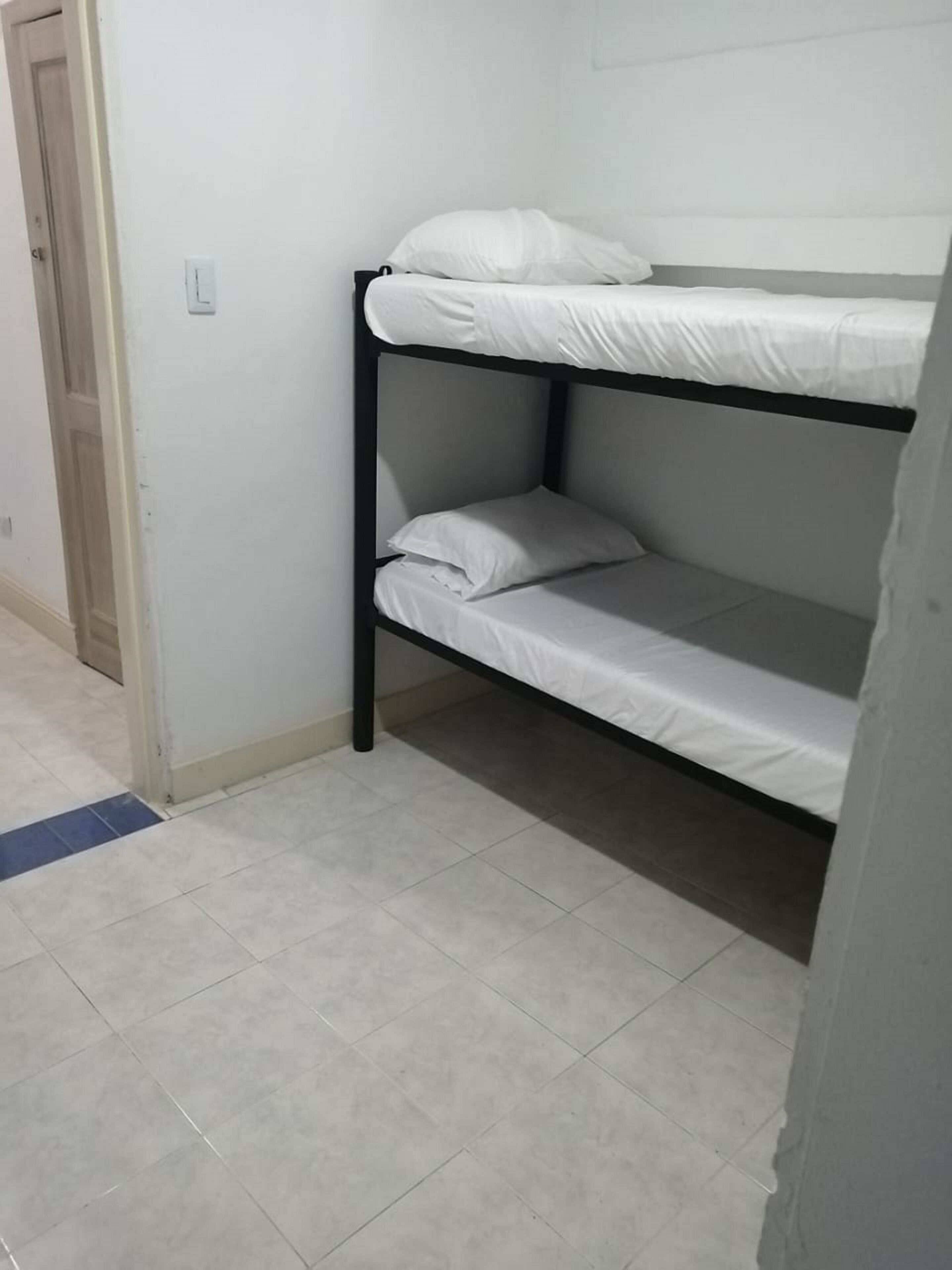 A bunk bed in a room with a tiled floor and a door in the background.