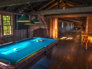 Een pooltafel met ballen, houten wanden en een houten plafond.