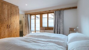 Une chambre à coucher avec un grand lit, une armoire en bois et une fenêtre avec des rideaux.