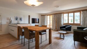 Un salon moderne avec une table à manger en bois, des fauteuils en cuir noir, une table basse ronde et un canapé noir.