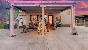 A rustic building with a covered porch, a Christmas tree, and farm-themed decorations. - BYRD'S FARMHOUSE CHICK-INN COOP (Shiner)