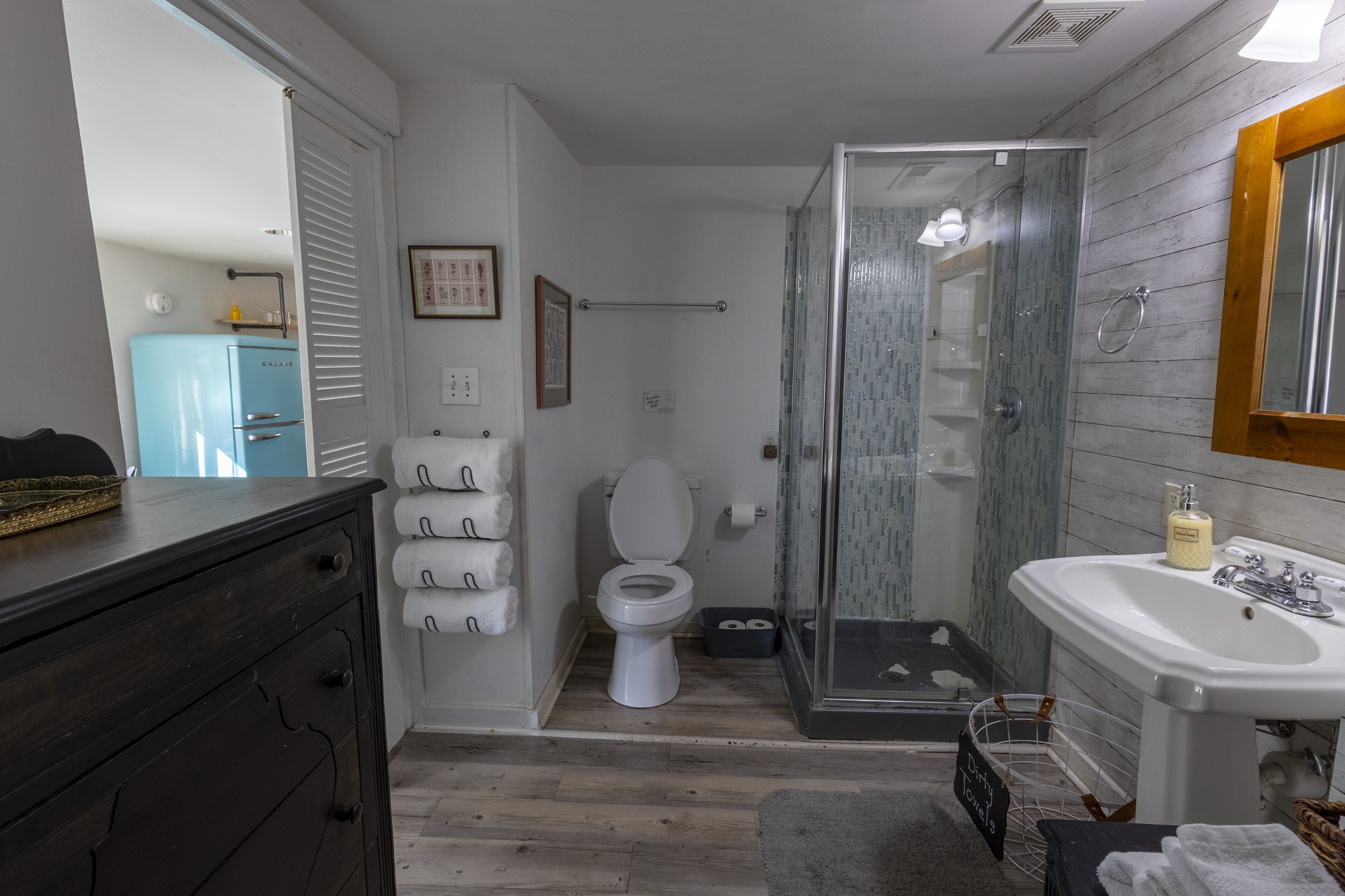 Une salle de bain équipée de toilettes, d’une douche, d’un lavabo et d’un meuble en bois.