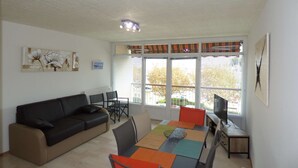 Ein Wohnzimmer mit einer Couch, einem Esstisch, Stühlen und einem Fernseher.