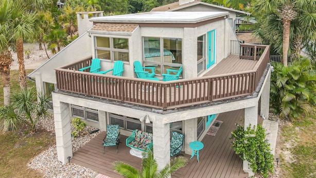 A two-story house with a deck, large windows, and outdoor seating.