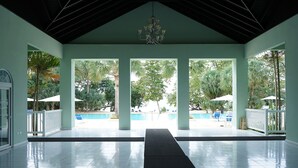 Un espace extérieur abrité comprenant une piscine, des palmiers et un lustre.