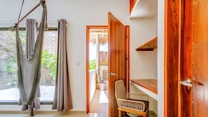 A room with a hammock, a wooden chair, and a wooden door. - Experience Tulum’s laidback yet vibrant lifestyle in this cozy apartment (Tulum)