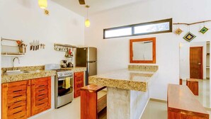A modern kitchen with granite countertops, wooden cabinets, stainless steel appliances, and pendant lighting. - Experience Tulum’s laidback yet vibrant lifestyle in this cozy apartment (Tulum)
