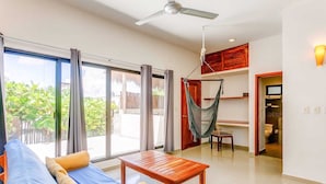 A spacious living area with a sofa, a wooden table, and a hammock. - Experience Tulum’s laidback yet vibrant lifestyle in this cozy apartment (Tulum)