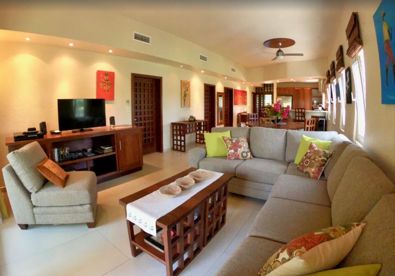 A living room with a sofa, armchairs, a coffee table, a TV, and a dining area with chairs and a table.