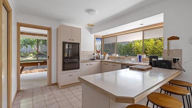 Een moderne keuken met een groot schiereiland, inbouwapparatuur en grote ramen met uitzicht op de omgeving.