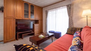 Una sala de estar con armarios de madera, un televisor de pantalla plana, un sofá y una mesa de centro.