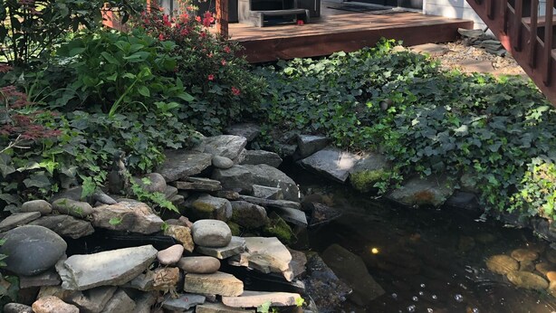 En træterrasse med jacuzzi og en springvand i sten.