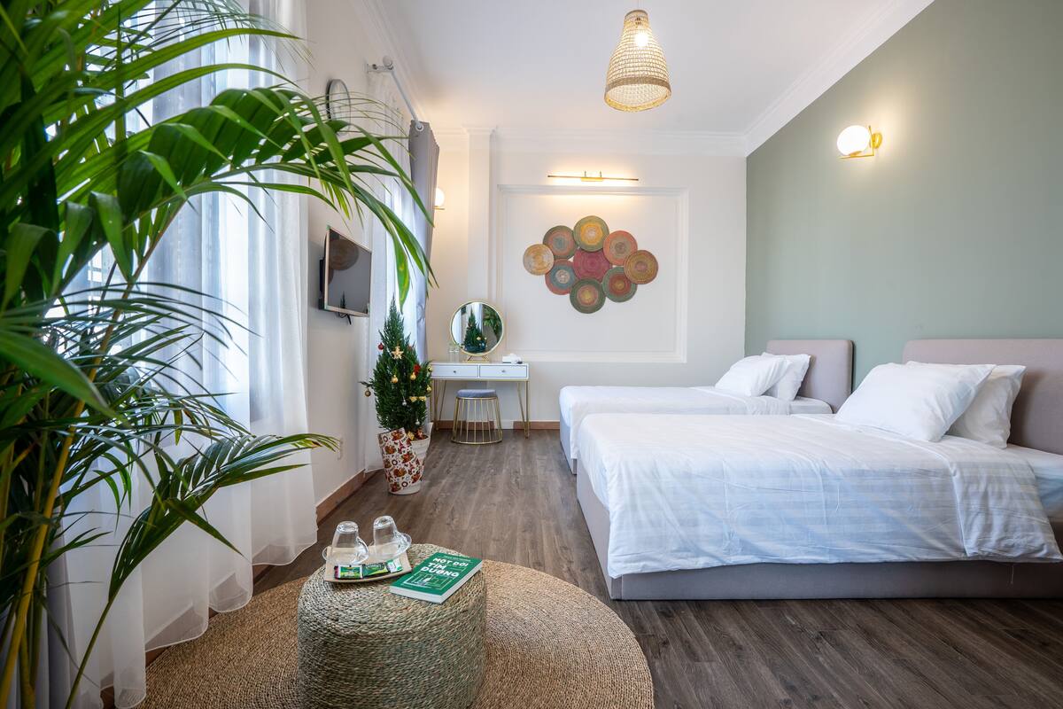 A modern bedroom with a bed, a desk, and a large plant.