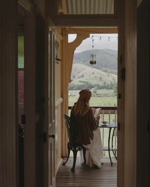 A person sitting on a bench on a wooden deck, reading a book.