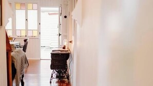 Un couloir avec un plancher en bois, une machine à coudre et un lit recouvert d’une couverture.