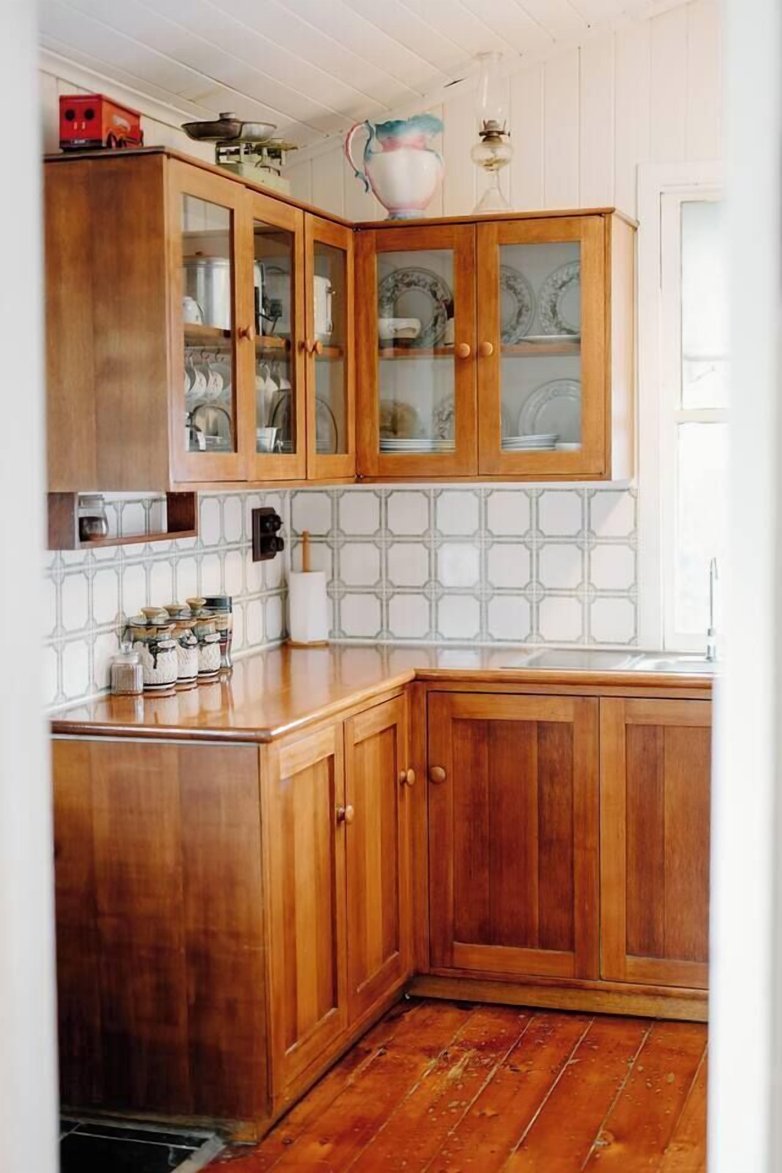 A kitchen with wooden cabinets, a tiled backsplash, and a wooden countertop.
