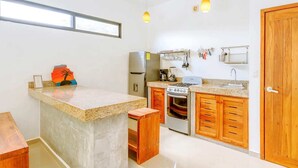 A compact kitchen with a central island, built-in oven, and wooden cabinets. - Stay in the heart of Tulum! footsteps away from the most vibrant street in town (Tulum)