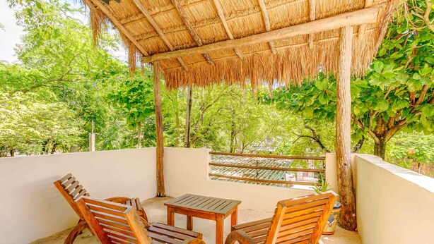 A covered outdoor seating area with wooden furniture and a thatched roof. - Stay in the heart of Tulum! footsteps away from the most vibrant street in town (Tulum)