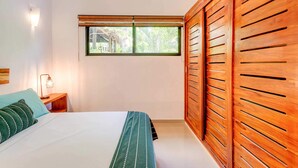 A bedroom with a bed, a nightstand, a window, and wooden paneling. - Stay in the heart of Tulum! footsteps away from the most vibrant street in town (Tulum)
