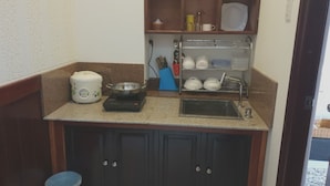 A compact kitchen with a built-in stove, a sink, and a dish rack. - TiMee Hotel & Apartment (Nam Nha Trang)