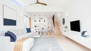 A modern living room with a sofa, coffee table, and a staircase leading to a kitchen.