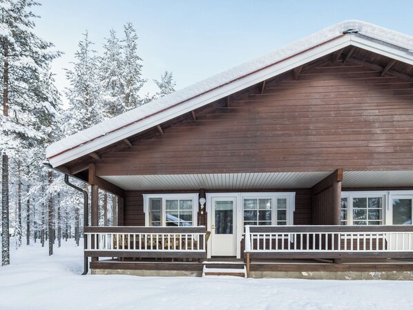 Een houten hut met een veranda, omringd door met sneeuw bedekte bomen.