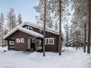 A wooden cabin with a porch, surrounded by snow-covered trees. - Albatrossi by Interhome (Kittilä)