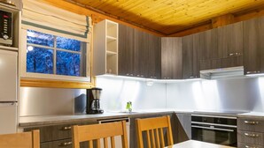 A modern kitchen with wooden cabinets, a built-in oven, and a coffee maker. - Albatrossi by Interhome (Kittilä)