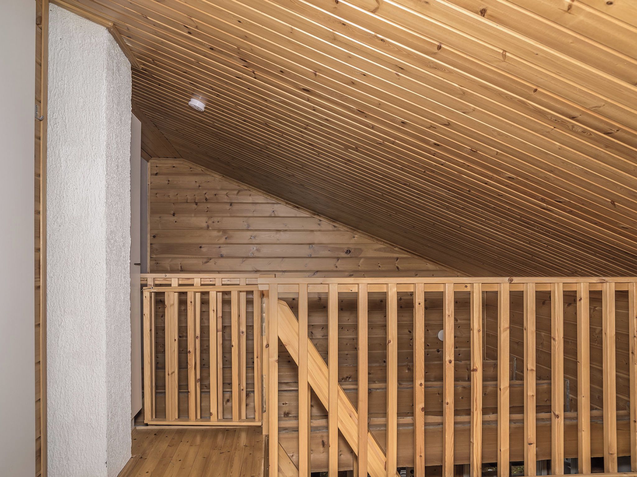 Eine Holztreppe führt zu einem Dachboden mit geneigter Decke.
