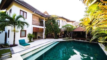 A residential property with a swimming pool, a balcony, and tropical plants.