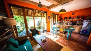 A cozy room with a wooden table, a sofa, and a kitchen area with a refrigerator and various items on the counter. - Easy Surf Villa (Pererenan)