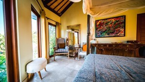 A bedroom with a large bed, a chair, a desk, and a mirror. There is a window with curtains and a painting on the wall. - Easy Surf Villa (Pererenan)