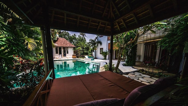 A poolside lounge with a view of a pool and tropical vegetation. - Easy Surf Villa (Pererenan)