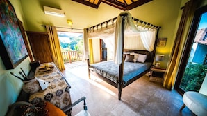 A four-poster bed with a canopy, a sofa, a small table, and a chair in a room with a balcony. - Easy Surf Villa (Pererenan)