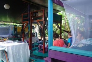 A room with a bed, a table with items on it, and a window with a view of greenery.
