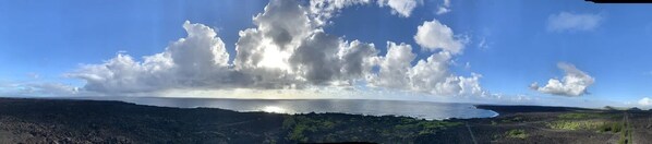 A coastal landscape with a road leading to the sea, surrounded by greenery and a clear sky. - Cinderland EcoVillage - Hostel (Pahoa)