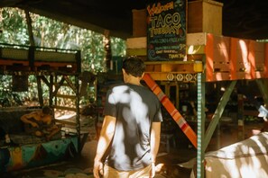 A man standing in front of a taco stand with a sign advertising tacos and a family dinner.