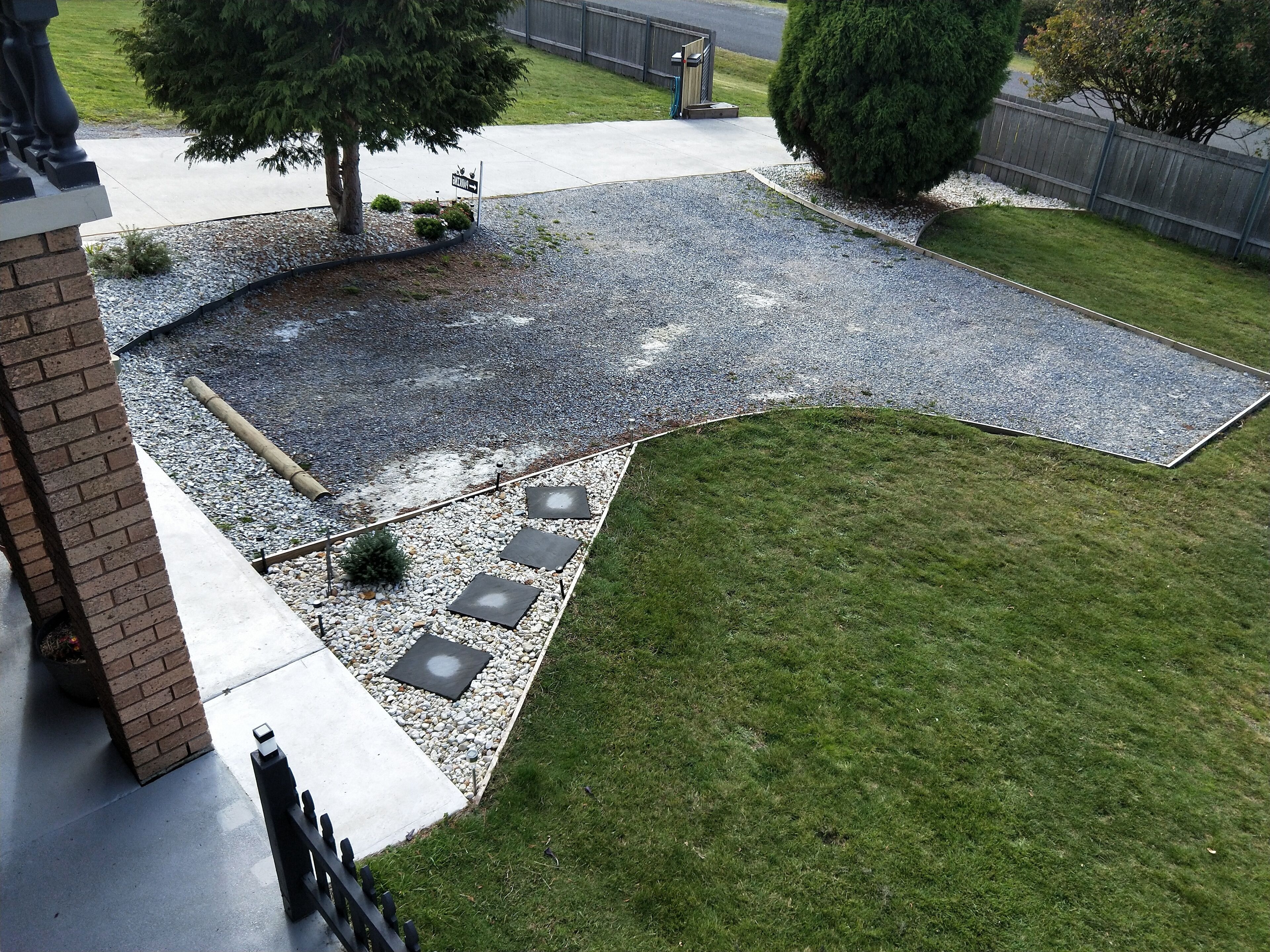 Uma área externa ajardinada com um caminho pavimentado, gramado e trilha de cascalho.
