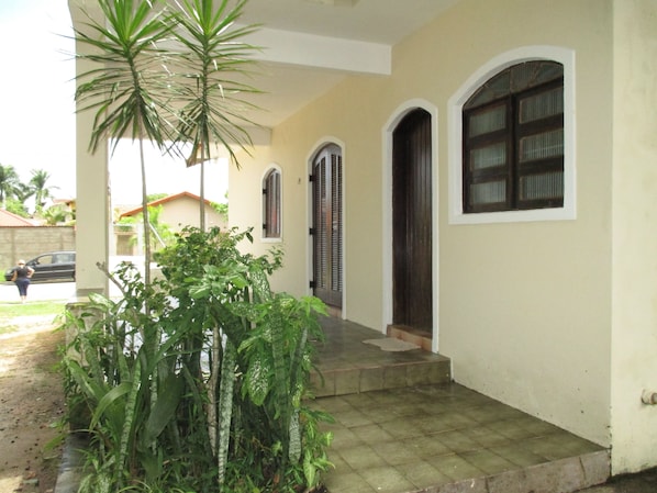 A house with a covered porch, a staircase leading to the entrance, and a car parked outside.