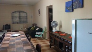 Un espace de vie compact comprenant une table à manger, un canapé, un ventilateur et un réfrigérateur.