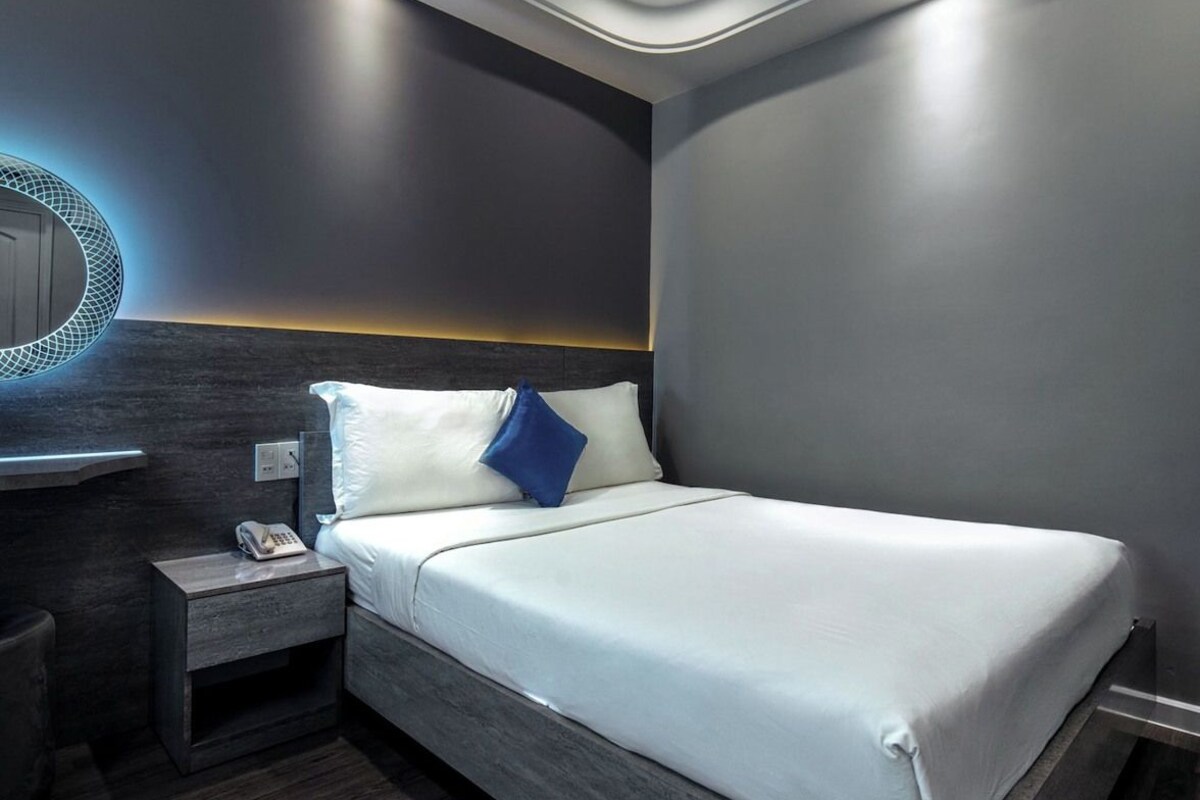 Ein modernes Schlafzimmer mit Bett, Nachttisch und Wandleuchte.