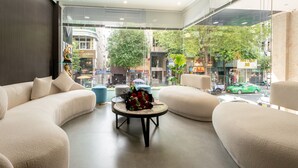 A modern hotel lobby with a large window, a sofa, a coffee table with flowers, and a view of the street outside. - Ruby Saigon Hotel - Ben Thanh (Ho Chi Minh City)