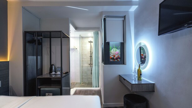 A modern hotel room with a bed, a wardrobe, a vanity with a mirror, and a TV mounted on the wall. - Ruby Saigon Hotel - Ben Thanh (Ho Chi Minh City)