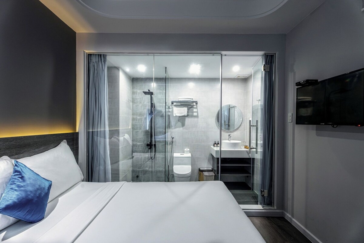 Ein Hotelzimmer mit Bett, Duschbereich, Waschbecken und Fernseher.