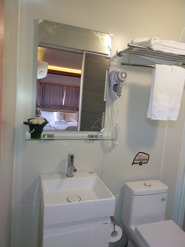 A bathroom with a white sink, a toilet, a hairdryer, and a towel rack.