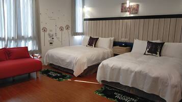 A hotel room with two beds, a red sofa, wooden flooring, and a wall with decorative stickers.